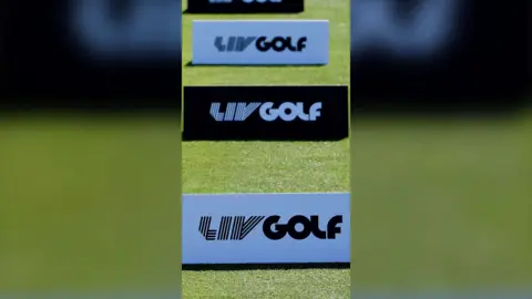 Three 'LIV Golf' ad boards stood upright on a patch of green grass
