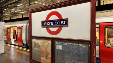 Barons Court Tube roundel with Tube train in background