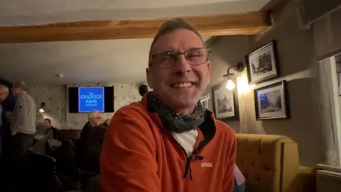 Gareth Jones, in an orange fleece sat in a pub