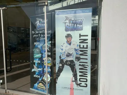 A poster advertising the Solway Sharks games with an ice hockey player and the word "commitment" on the side