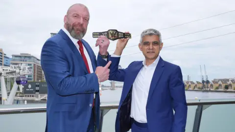 PA Media Mayor of London Sadiq Khan (right) holds aloft a gifted mini replica WWE Championship belt, with Paul "Triple H" Levesque, Head of Creative and Chief Content Officer, WWE, after a meeting at City Hall, London.