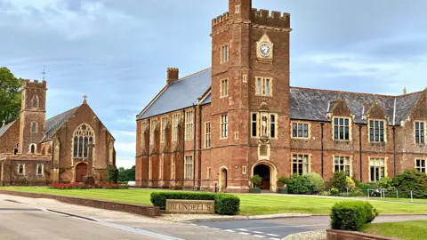 PA Wire Entrance to Blundell's School, Tiverton, Devon. A green lawn is pictured in front of the large brick building. 