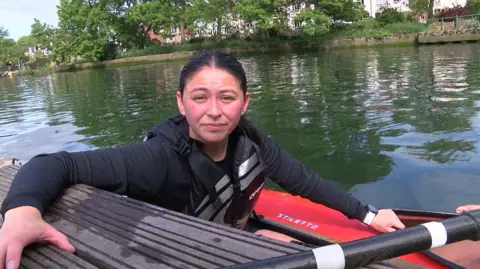 A girl with black hair and sat in a canoe on the river