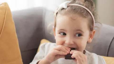 Little girl eating a piece of chocolate