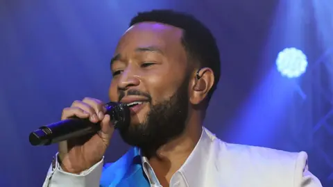 Musician John Legend sings into a microphone