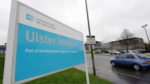 Pacemaker A sign outside the Ulster Hospital that says:  "South Eastern Health and Social Care Trust" in black writing on a white background and the words "Ulster Hospital, part of the south eastern trust group of hospitals" in white writing on a light blue backgrounds