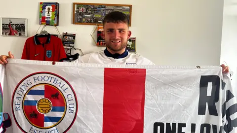 Charlie is posing and holding his thatcham royals flag