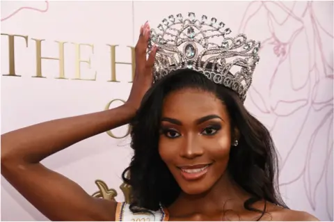 Getty Images Lalela Mswane holding her large diamond crown and smiling.