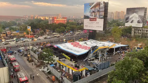 A huge ad billboard can be seen collapsed onto a petrol station and some housing in a suburb of Mumbai, India.
