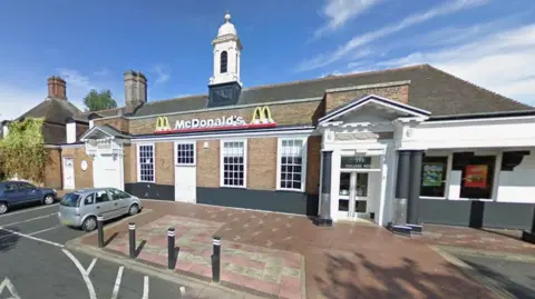 A McDonald’s restaurant with a small car park and a white entrance with columns at the front.
