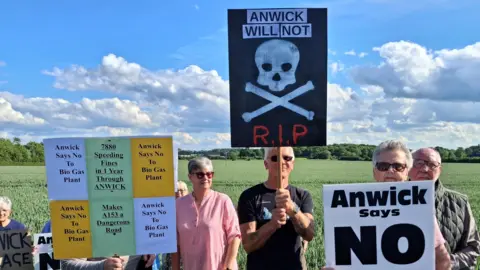 LDRS A group of campaigners standing in front of a field holding up signs including 'Andwick says no to biogas plant'.