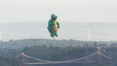 A giant green dragon flying above the Clifton Suspension Bridge in Bristol.