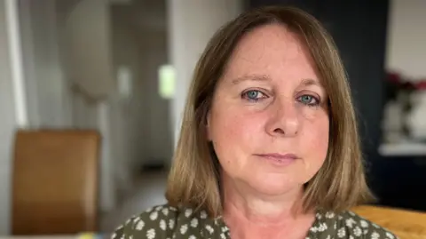 BBC A white woman with brown / blonde hair is sitting looking directly at the camera. 