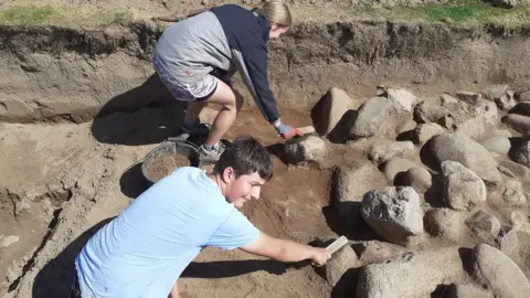 Gwynedd Archaeological Trust Experts uncover roundhouse at the 125-acre Dinas Dinlle site