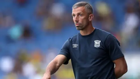Getty Images Gary O'Neil, the Ipswich Town manager, wearing a blue club T-shirt. The background is blurred but he appears to be in a stadium.