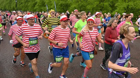 Pacemaker A mix of male and female runners dressed as where's wally running together, in red and white striped tops with red and white striped hats.