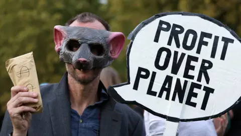 Reuters An Extinction Rebellion activist wears a pig mask and holds a sign which reads "profit over planet".