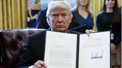 US President Donald Trump displays one of five executive orders he signed related to the oil pipeline industry in the oval office of the White House in Washington, DC, USA, 24 January 2017