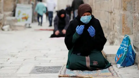 Reuters A Muslim woman wearing a face mask and rubber gloves prays