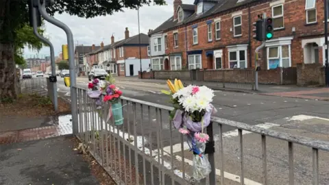 Floral tributes tied to the barrier by the pedestrian crossing on Carholme Road in Lincoln