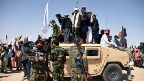 Getty Images Afghan Taliban militants and residents stand on a armoured Humvee vehicle of the Afghan National Army as they celebrate a ceasefire on the third day of Eid in Maiwand district of Kandahar province