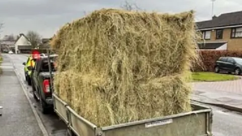 Northamptonshire Police Car pulling trailer containing several unsecured bales of hay