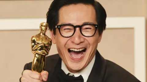 Reuters Ke Huy Quan smiling with his Oscar