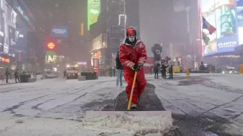 Reuters A worker clears snow in Times Square