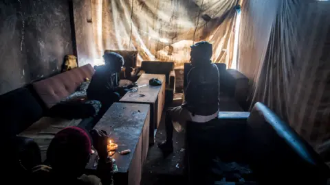 BBC/SHIRAAZ MOHAMED Residents as seen sitting in a room of the derelict San Jose building in Johannesburg, South Africa