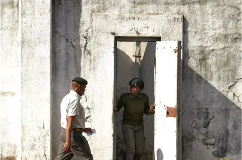 JEKESAI NJIKIZANA/ AFP Prison guards standing by a white door at Harare Central Prison.