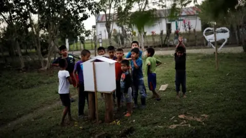 Reuters Children gather near a makeshift altar to Jakelin Caal in the village of San Antonio Secortez. Photo: 22 December 2018