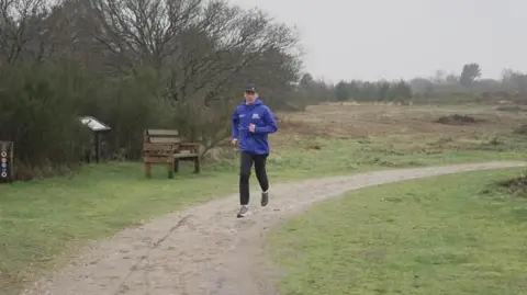 Shaun Whitmore/BBC Logan training on a woodland trail at Kelling Heath in a blue GB and NI jacket, black trousers and black cap on a grey, overcast day in North Norfolk.