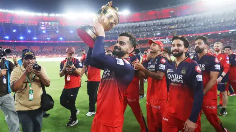 Virat Kohli and his RCB team-mates are photographed lifting the trophy