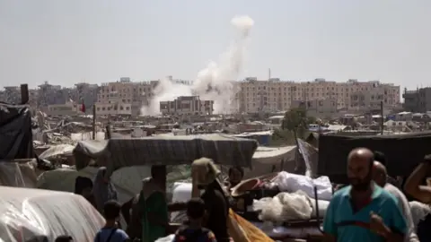 EPA people evacuate as smoke rises amid the advance of Israeli military vehicles in an area sheltering internally displaced Palestinians in Khan Yunis, southern Gaza Strip, on August 18, 2024.