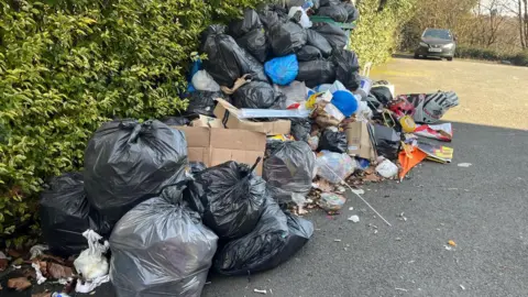 Kantong sampah hitam sampah yang ditumpuk tinggi di tanah