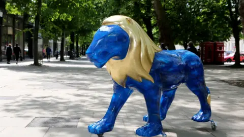 Anna Lythgoe A blue lion sculpture with a gold mane on Cheltenham Promenade