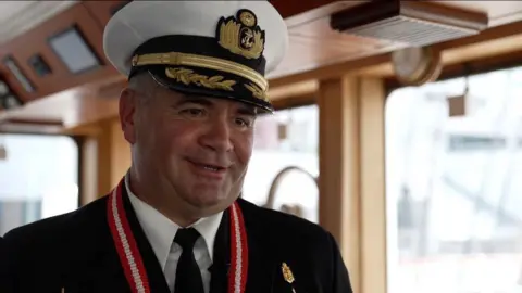 A Peruvian Navy Commander smiles. He is wearing full military uniform