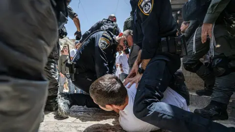 Getty Images Two Israeli officers straddle a man on the ground in East Jerusalem as the Jerusalem Day parade becomes violent