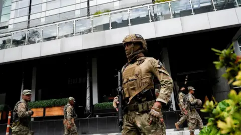 Reuters photos of the members of the armed with the national service in Panama in Panama who wear masks and guard the hotel where the migrants remain the cheerful