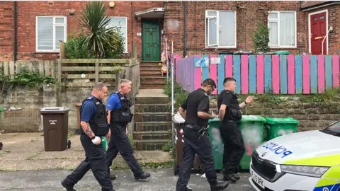 BBC Police walking down   Costock Avenue, Sherwood, connected  the greeting  of the tragedy. Four officers locomotion  unneurotic  down   a residential street.