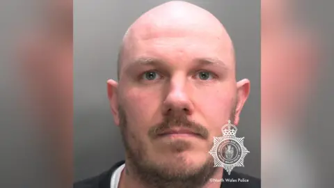 North Wales Police A police mugshot of Miles Cross, a bald man with a beard and moustache.