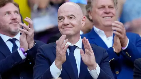Fifa president Gianni Infantino wearing a suit and clapping