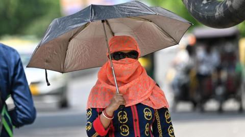 A woman out on a hot day in Delhi's Pitampura locality on April 28, 2024
