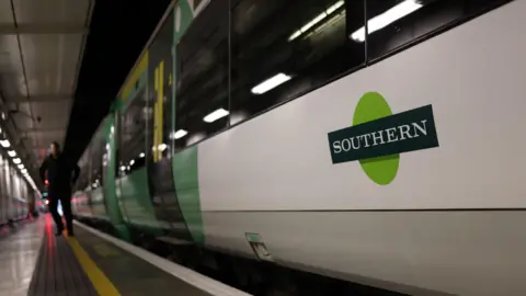 A train with Southern's Green and white logo stands at the platform of Victoria Station in London.