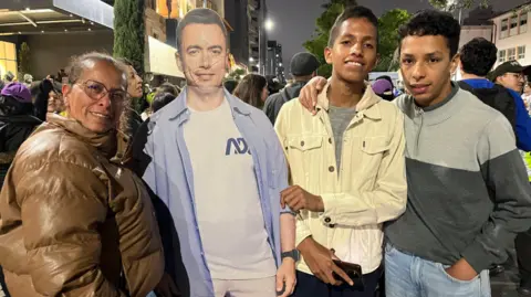 Ecuadorian supporters of Daniel Noboa stand next to a cardboard cut out of the president