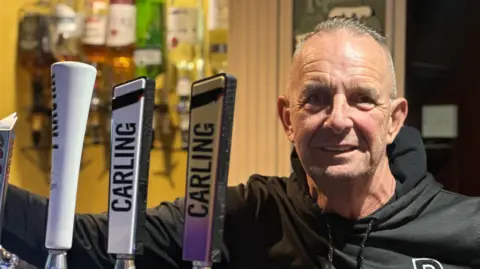 Tom Paterson Man in black hoodie stood in a pub