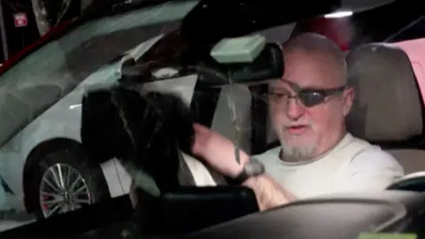 Stewart Rhodes wearing an eye patch leaving prison in a car 