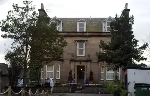 PA Media Exterior of the Wilson family home, scene of the murder, with forensic officers wearing white and police caution tape around the property