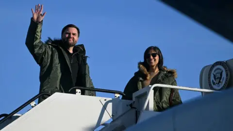 Jim Watson/Pool via Reuters JD Vance, waving, and Usha Vance, smiling, board Air Force Two. They are both wearing thick khaki coats