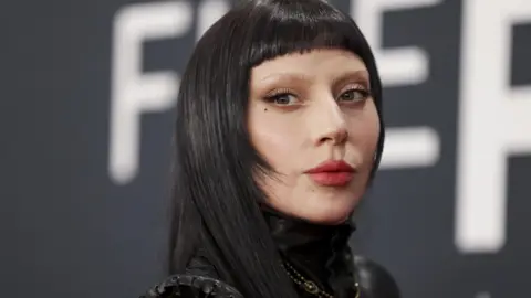 EPA Close up of Lady Gaga with long black hair and spare make-up.